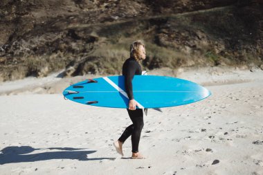 Palet ve okyanus kıyısında hidro elbiseli bir bodyboard sörfçü