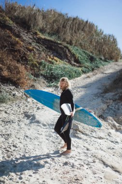 Palet ve okyanus kıyısında hidro elbiseli bir bodyboard sörfçü