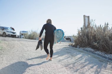 Palet ve okyanus kıyısında hidro elbiseli bir bodyboard sörfçü