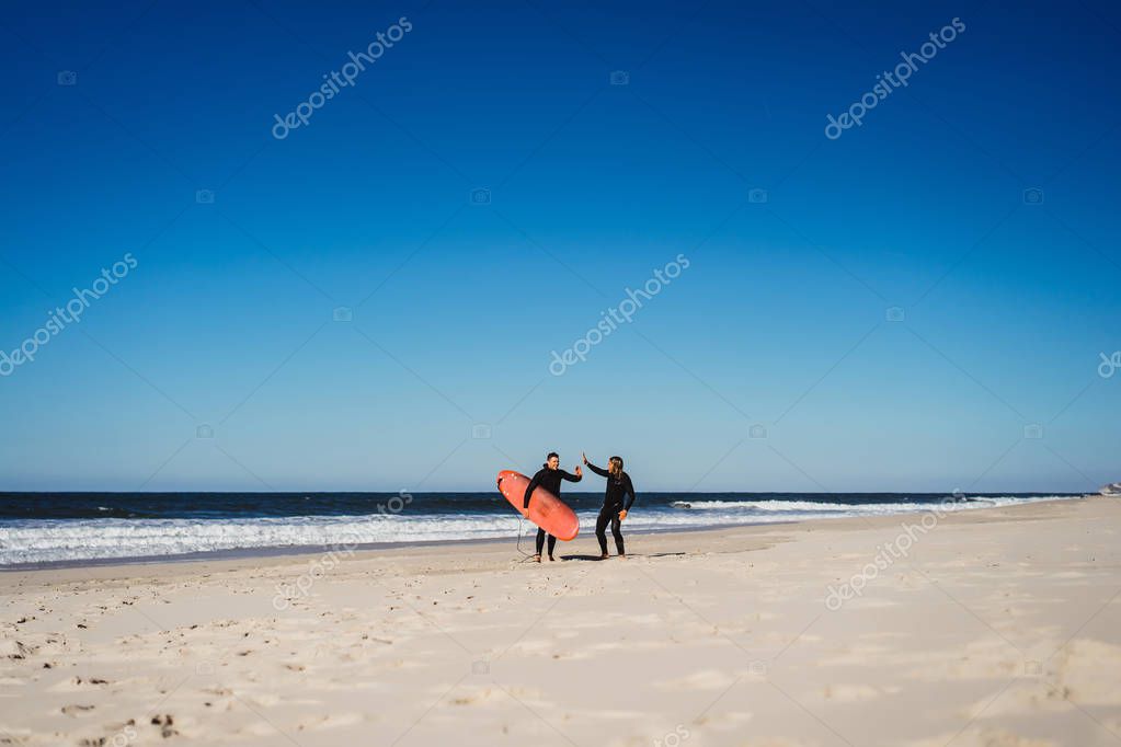 instructor de surf con un estudiante en el océano. Surfista en traje de