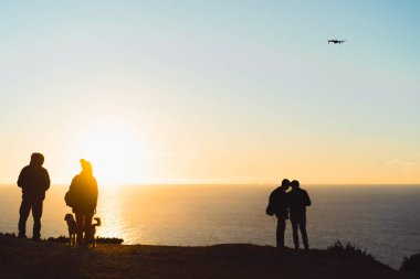 bir kayanın üzerinde gün batımını izlemek insanlar bir köpek, bir dron başlatma.