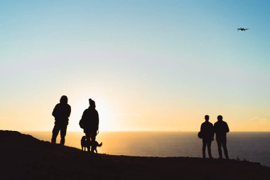 bir kayanın üzerinde gün batımını izlemek insanlar bir köpek, bir dron başlatma.
