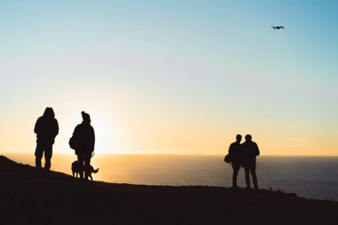 bir kayanın üzerinde gün batımını izlemek insanlar bir köpek, bir dron başlatma.