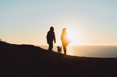bir kayanın üzerinde gün batımını izlemek insanlar bir köpek, bir dron başlatma.