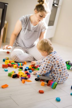 Çocuk, renkli çocuk yapım setiyle annesiyle oynuyor. Çocukların inşaat malzemelerinin ayrıntıları yere saçılmış..