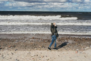 sıcak bir ceket, uzun saçlı kız soğuk Baltık Denizi sahil boyunca yürüyüş