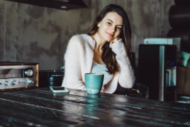 büyüleyici bir gülümseme ve kahve içme ve bir smartphone kullanarak ifade kahverengi gözlü güzel bir esmer kız