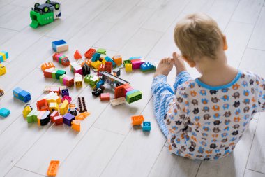 Çocuk, renkli çocuk yapım setiyle annesiyle oynuyor. Çocukların inşaat malzemelerinin ayrıntıları yere saçılmış..