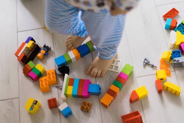 Çocuk, renkli çocuk yapım setiyle annesiyle oynuyor. Çocukların inşaat malzemelerinin ayrıntıları yere saçılmış..