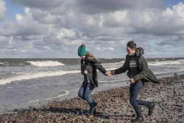 genç bir çift hafta sonları deniz kenarı soğuk Baltık Denizi, kumsalı, sıcak ceketler, Aile hafta sonu erkek ve kadın plajda çalışan harcama aşık.
