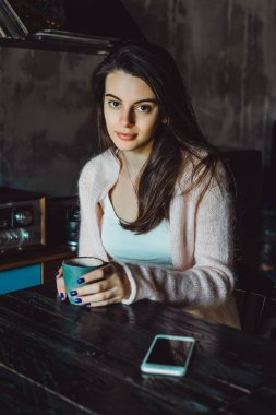 büyüleyici bir gülümseme ve kahve içme ve bir smartphone kullanarak ifade kahverengi gözlü güzel bir esmer kız