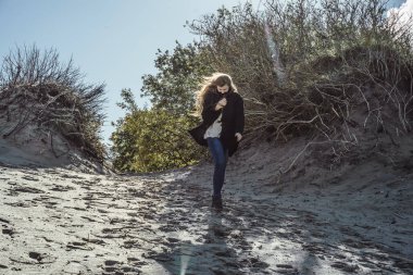 sıcak bir ceket, uzun saçlı kız soğuk Baltık Denizi sahil boyunca yürüyüş