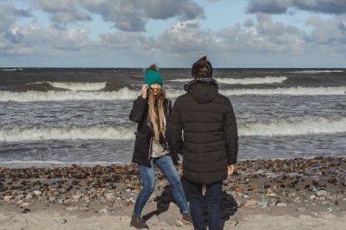 genç bir çift hafta sonları deniz kenarı soğuk Baltık Denizi, kumsalı, sıcak ceketler, Aile hafta sonu erkek ve kadın plajda çalışan harcama aşık.