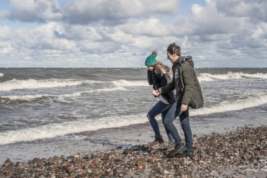 genç bir çift hafta sonları deniz kenarı soğuk Baltık Denizi, kumsalı, sıcak ceketler, Aile hafta sonu erkek ve kadın plajda çalışan harcama aşık.