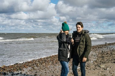 genç bir çift hafta sonları deniz kenarı soğuk Baltık Denizi, kumsalı, sıcak ceketler, Aile hafta sonu erkek ve kadın plajda çalışan harcama aşık.