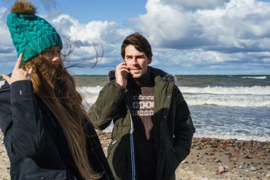 genç bir çift hafta sonları deniz kenarı soğuk Baltık Denizi, kumsalı, sıcak ceketler, Aile hafta sonu erkek ve kadın plajda çalışan harcama aşık.