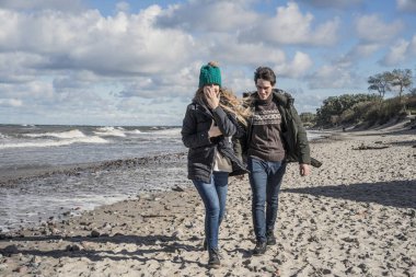 genç bir çift hafta sonları deniz kenarı soğuk Baltık Denizi, kumsalı, sıcak ceketler, Aile hafta sonu erkek ve kadın plajda çalışan harcama aşık.