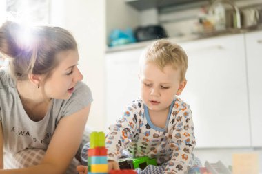 Çocuk, renkli çocuk yapım setiyle annesiyle oynuyor. Çocukların inşaat malzemelerinin ayrıntıları yere saçılmış..