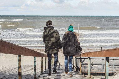 genç bir çift hafta sonları deniz kenarı soğuk Baltık Denizi, kumsalı, sıcak ceketler, Aile hafta sonu erkek ve kadın plajda çalışan harcama aşık.