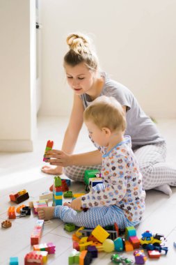 Çocuk, renkli çocuk yapım setiyle annesiyle oynuyor. Çocukların inşaat malzemelerinin ayrıntıları yere saçılmış..