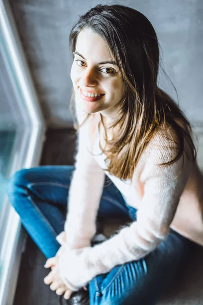 beautiful brunette girl with expressive brown eyes and charming cute smile close-up portrait indoors. interesting light through small holes