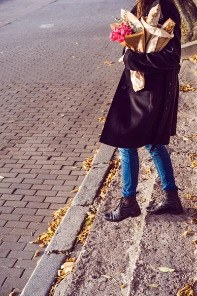 beautiful French woman brunette in a red beret with a bouquet of flowers and French baguettes under her arm walks through the park in Paris in a European city, in Paris