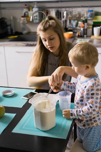 朝のパジャマの男の子と台所でアップルパイを調理しおもちゃで遊ぶ — ストック写真