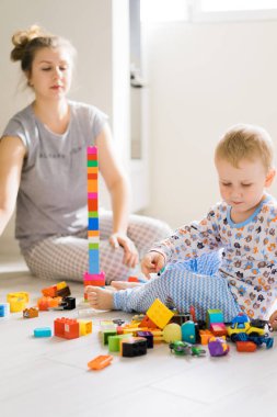 Çocuk, renkli çocuk yapım setiyle annesiyle oynuyor. Çocukların inşaat malzemelerinin ayrıntıları yere saçılmış..