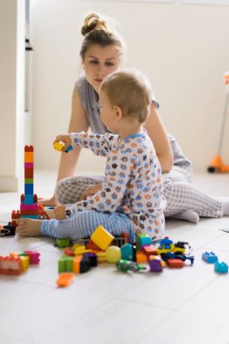 Çocuk, renkli çocuk yapım setiyle annesiyle oynuyor. Çocukların inşaat malzemelerinin ayrıntıları yere saçılmış..
