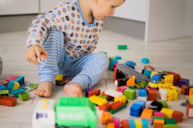 Çocuk, renkli çocuk yapım setiyle annesiyle oynuyor. Çocukların inşaat malzemelerinin ayrıntıları yere saçılmış..