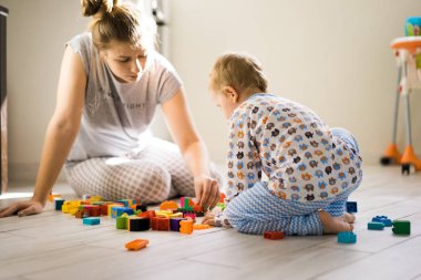 Çocuk, renkli çocuk yapım setiyle annesiyle oynuyor. Çocukların inşaat malzemelerinin ayrıntıları yere saçılmış..