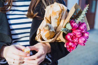 Genç güzel kız Fransız kadın esmer kırmızı bere ve siyah bir ceket Avrupa şehri Street'te bir buket çiçek ve Fransız baget ile gider. Mutlu bir gülümseme ve büyüleyici bir bak, Paris Fransız tarzı