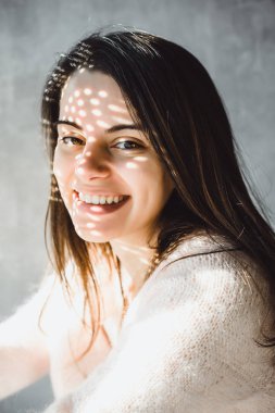 güzel esmer kız ifade kahverengi gözleri ve sevimli sevimli gülümseme yakın çekim portre kapalı. küçük deliklerden ilginç ışık