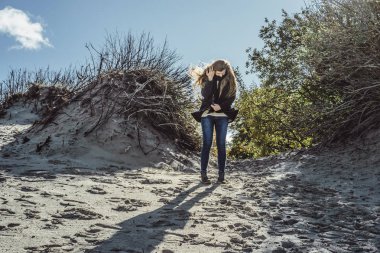 sıcak bir ceket, uzun saçlı kız soğuk Baltık Denizi sahil boyunca yürüyüş