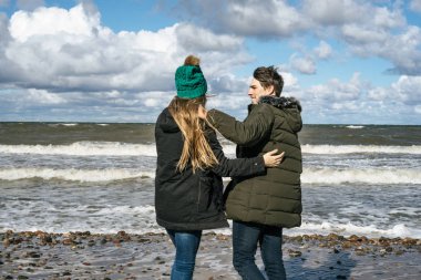 genç bir çift hafta sonları deniz kenarı soğuk Baltık Denizi, kumsalı, sıcak ceketler, Aile hafta sonu erkek ve kadın plajda çalışan harcama aşık.