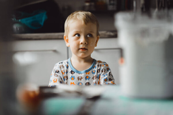 мальчик ребенок в пижаме утром с мамой приготовления яблочного пирога на кухне и играть с игрушками