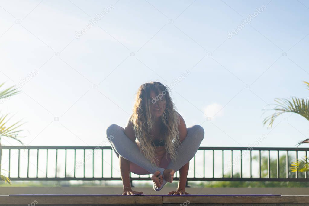 Young woman practicing yoga, advanced yoga outside.
