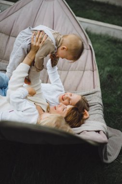 bir hamakta eğleniyor çocuk anne. Anne ve çocuklar bir hamak. Aile ile çocuk bahçesinde vakit geçiriyor.