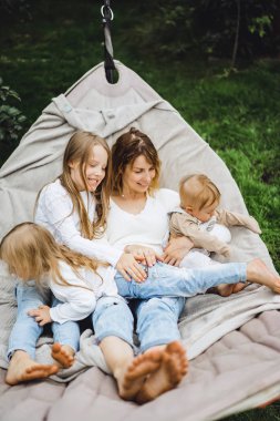 bir hamakta eğleniyor çocuk anne. Anne ve çocuklar bir hamak. Aile ile çocuk bahçesinde vakit geçiriyor.