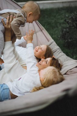 bir hamakta eğleniyor çocuk anne. Anne ve çocuklar bir hamak. Aile ile çocuk bahçesinde vakit geçiriyor.