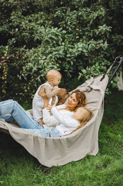 bir hamakta eğleniyor çocuk anne. Anne ve çocuklar bir hamak. Aile ile çocuk bahçesinde vakit geçiriyor.