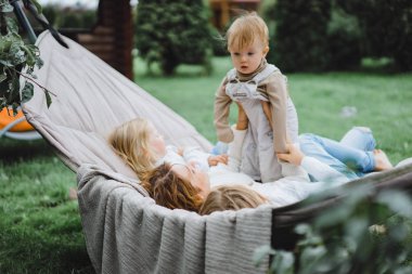 bir hamakta eğleniyor çocuk anne. Anne ve çocuklar bir hamak. Aile ile çocuk bahçesinde vakit geçiriyor.