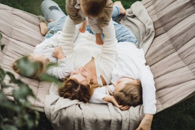 bir hamakta eğleniyor çocuk anne. Anne ve çocuklar bir hamak. Aile ile çocuk bahçesinde vakit geçiriyor.