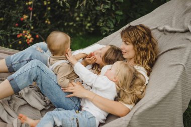 bir hamakta eğleniyor çocuk anne. Anne ve çocuklar bir hamak. Aile ile çocuk bahçesinde vakit geçiriyor.