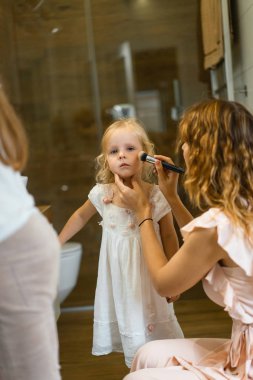 Anne ve kızı banyoda makyaj yapmak, aynanın önünde ruj uygulayın. Anne ve kızı birlikte vakit geçirmek iyi eğlenceler.