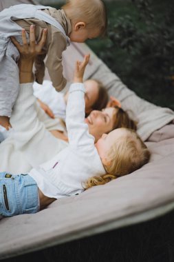 bir hamakta eğleniyor çocuk anne. Anne ve çocuklar bir hamak. Aile ile çocuk bahçesinde vakit geçiriyor.