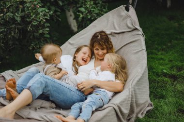 bir hamakta eğleniyor çocuk anne. Anne ve çocuklar bir hamak. Aile ile çocuk bahçesinde vakit geçiriyor.