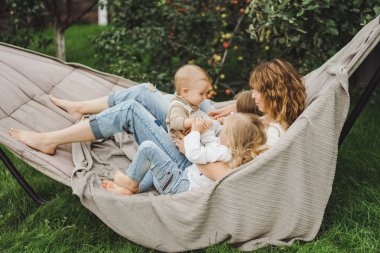 bir hamakta eğleniyor çocuk anne. Anne ve çocuklar bir hamak. Aile ile çocuk bahçesinde vakit geçiriyor.