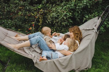 bir hamakta eğleniyor çocuk anne. Anne ve çocuklar bir hamak. Aile ile çocuk bahçesinde vakit geçiriyor.