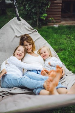 bir hamakta eğleniyor çocuk anne. Anne ve çocuklar bir hamak. Aile ile çocuk bahçesinde vakit geçiriyor.